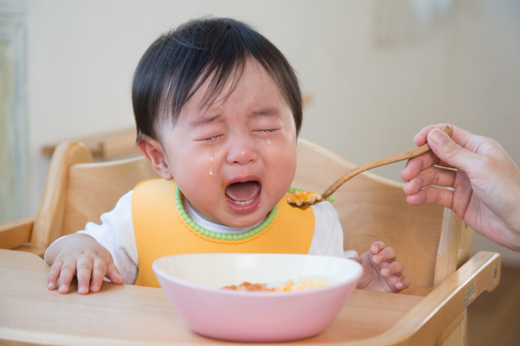 ごはんを食べながら泣く赤ちゃん