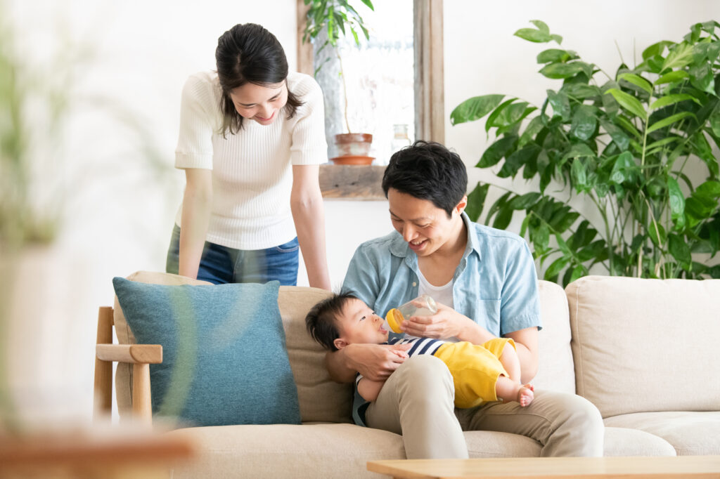 子どもにミルクを飲ましている夫婦