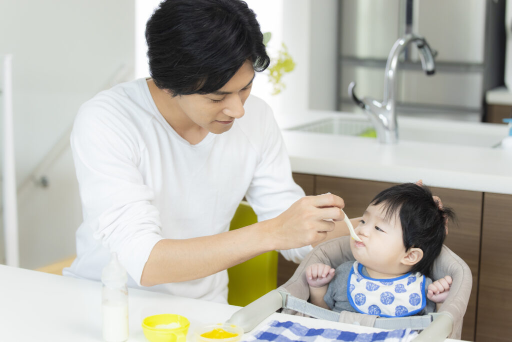 子どもに離乳食を食べさせているパパ