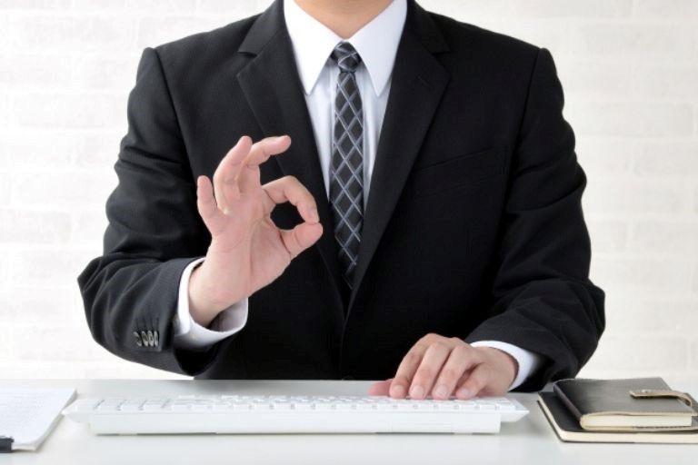 派遣社員のダブルワークは基本的にOKのイメージ図－スーツを着た男性がキーボードを打ちながら右手でOKサインをしている。