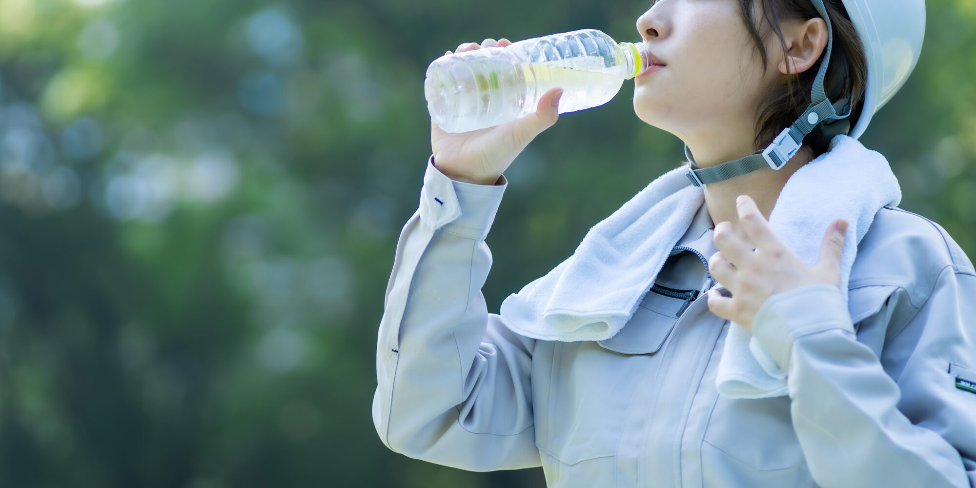 熱中症対策のため、ペットボトルの水を飲んでいる工場勤務の女性