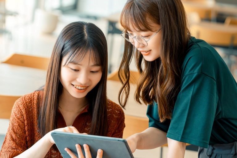 「中卒女性が効率良く仕事を探すためには？」のイメージ画像‐iPadを見ながら求人情報を確認している2人の女性