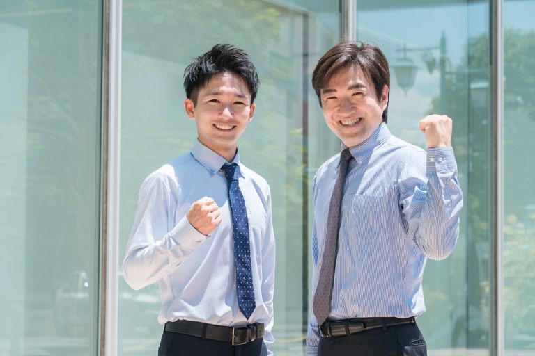 「製造業のやりがい」のイメージ画像‐ネクタイ姿の男性２名がガッツポーズをしてこちらを見ている。